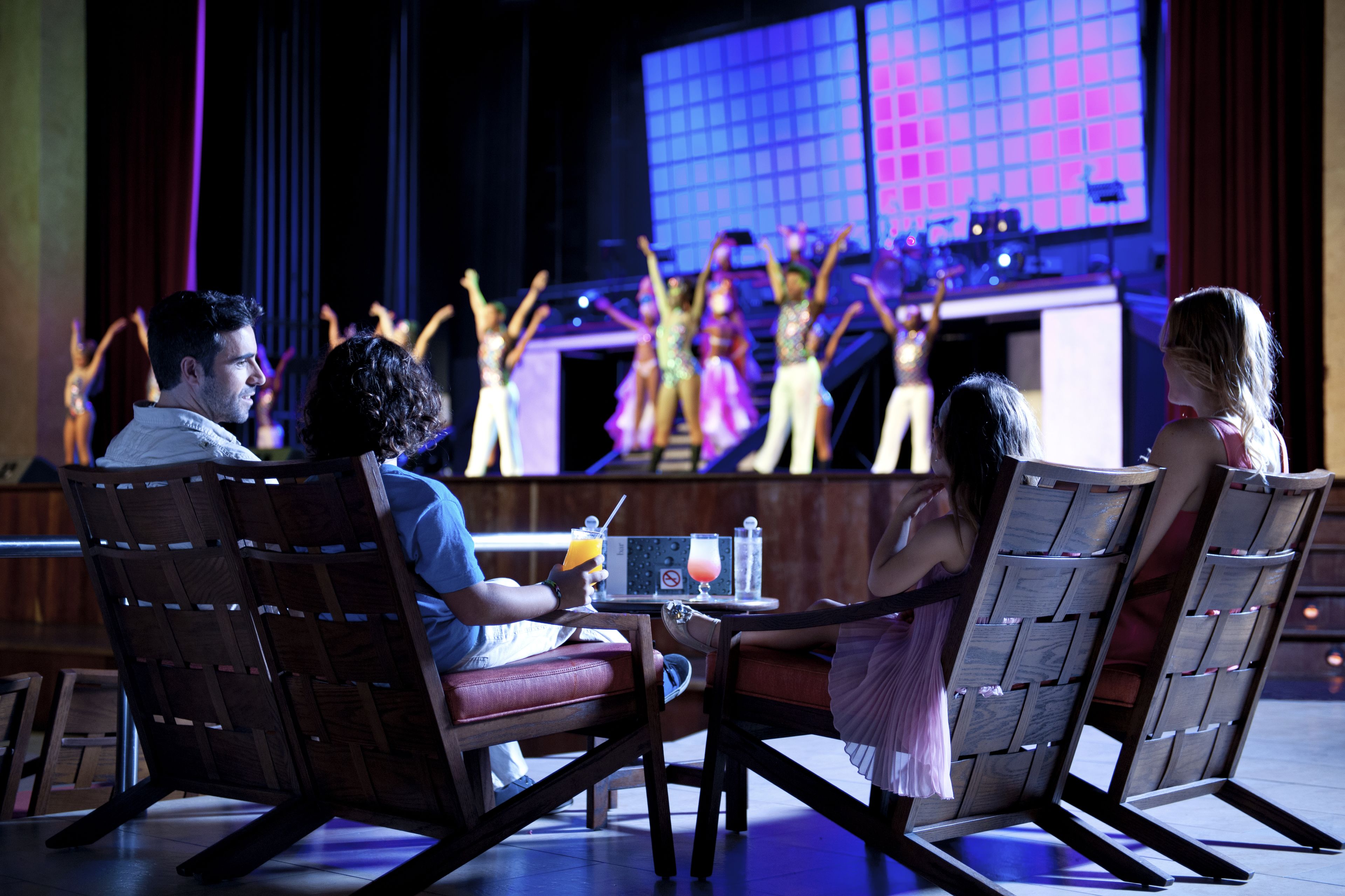 A group of people watching a performance on a stage with a large screen.