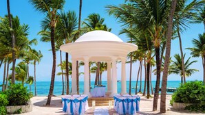 A beach wedding setup with a white gazebo, white and blue chairs, and a white aisle runner. - Barceló Bávaro Palace - All Inclusive (Punta Cana)