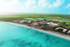 An aerial view of a coastal resort with a beach, clear turquoise waters, and a large building complex with multiple structures. - Barceló Bávaro Palace - All Inclusive (Punta Cana)