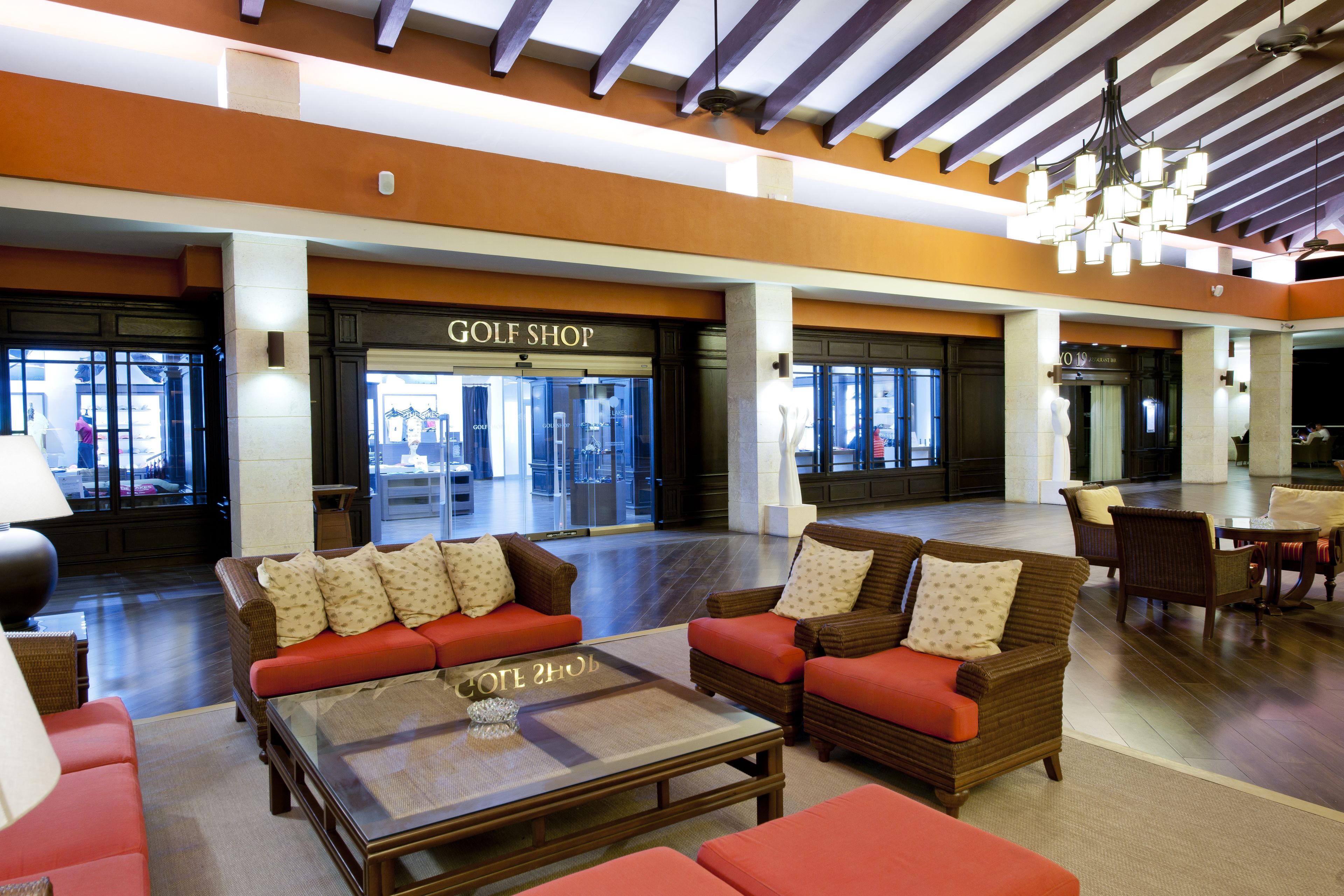 Um lobby com loja de golfe, assentos confortáveis e um candelabro.