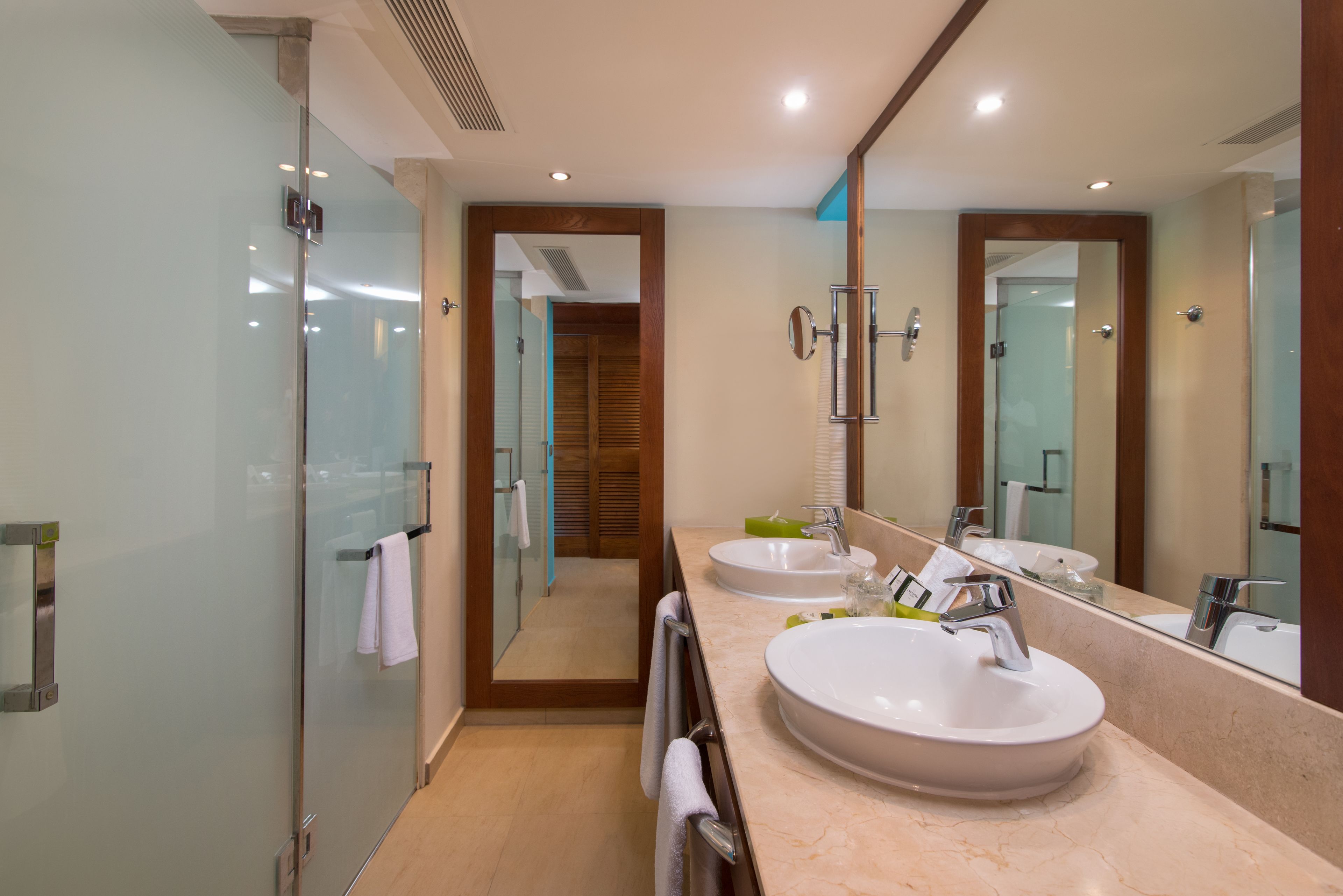 A modern bathroom with two sinks, a large mirror, and a glass shower enclosure.