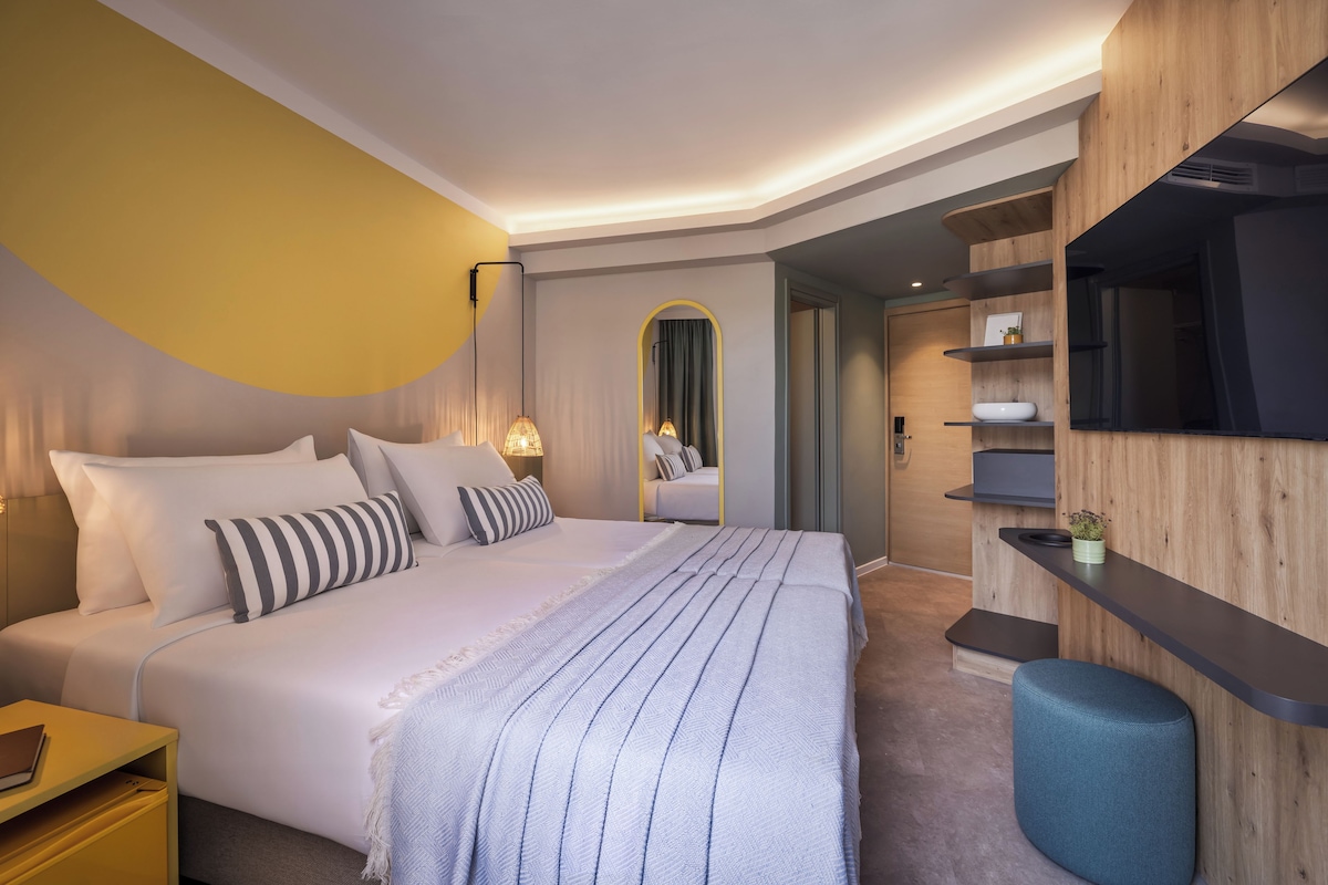 A modern bedroom with a large bed, bedside tables, a mirror, and built-in shelving.