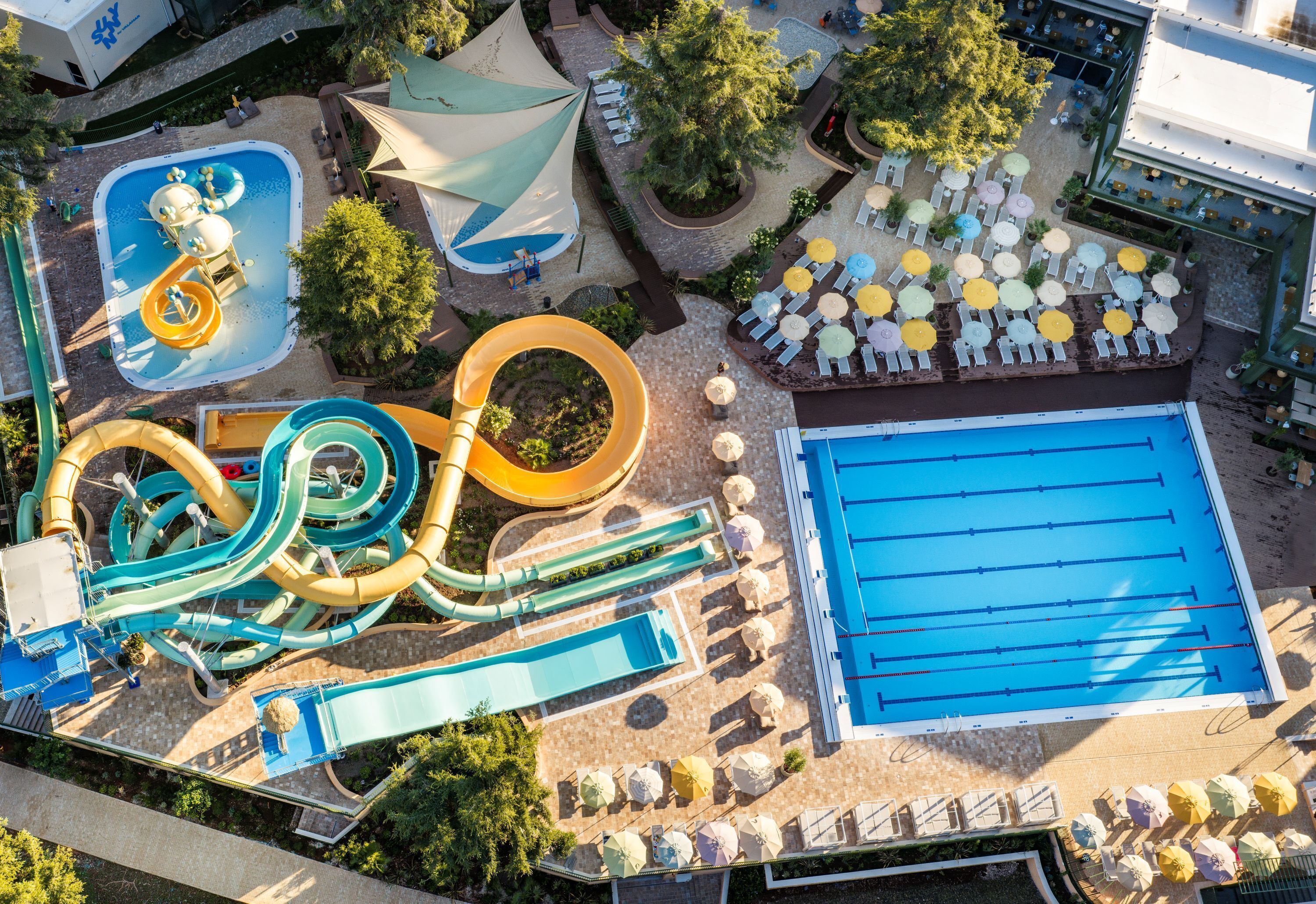 An aerial view of a water park with multiple slides, a swimming pool, and sun loungers.
