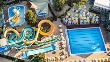 An aerial view of a water park with multiple slides, a swimming pool, and sun loungers.