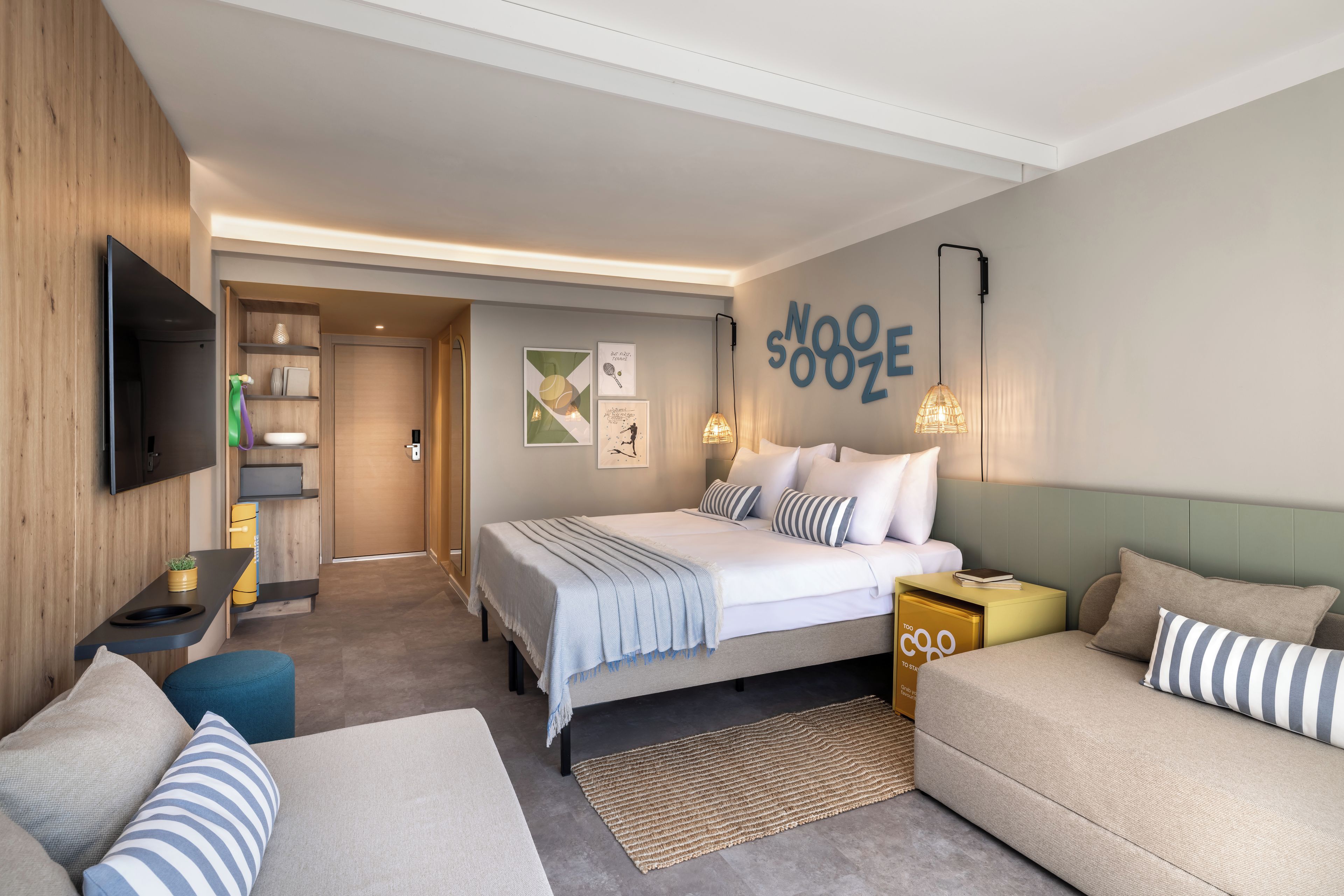 Et moderne hotelværelse med seng, sengeborde, fjernsyn og et billede hængende på væggen.