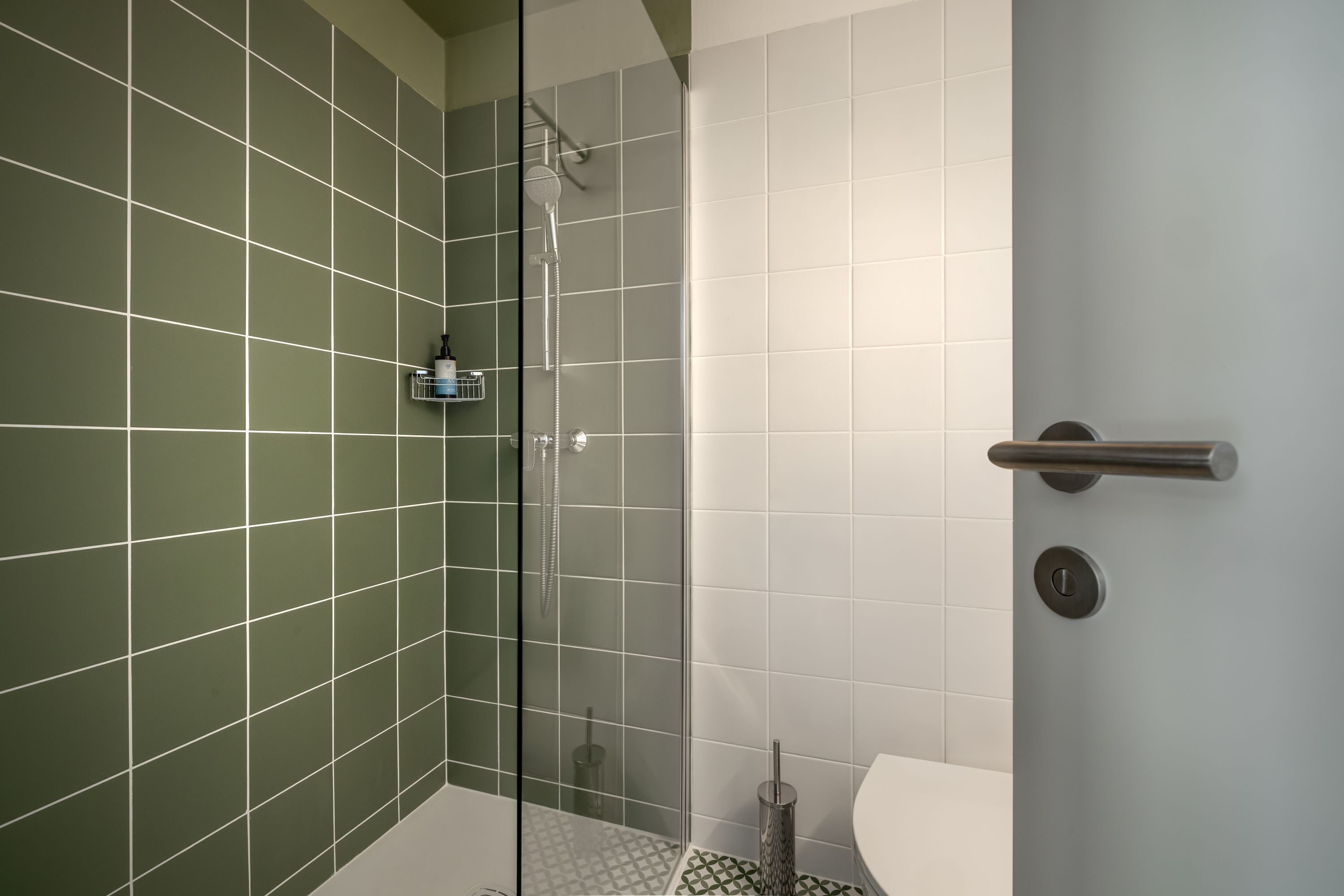 A modern bathroom with a shower, a toilet, and a glass door.