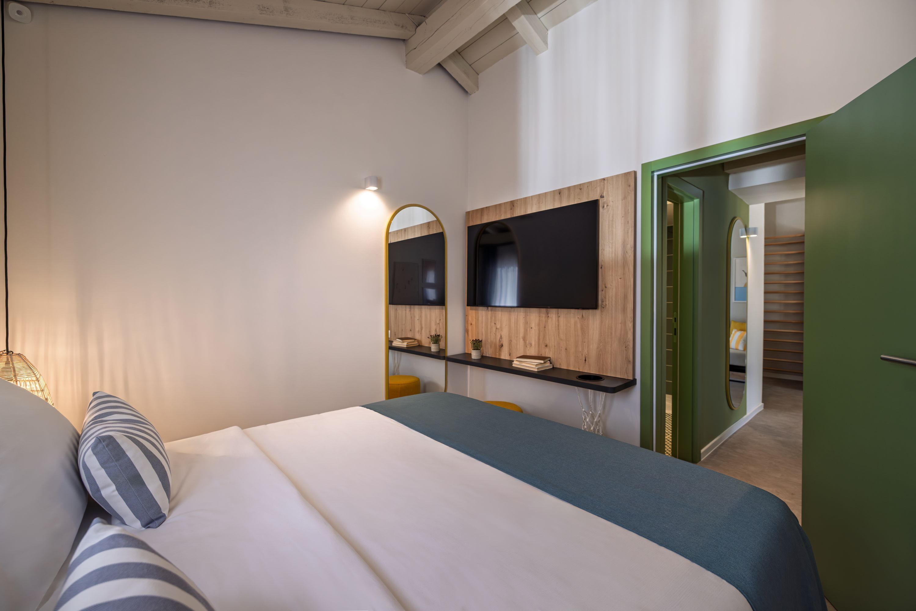 Une chambre à coucher avec un lit, un bureau, un miroir et une télévision.