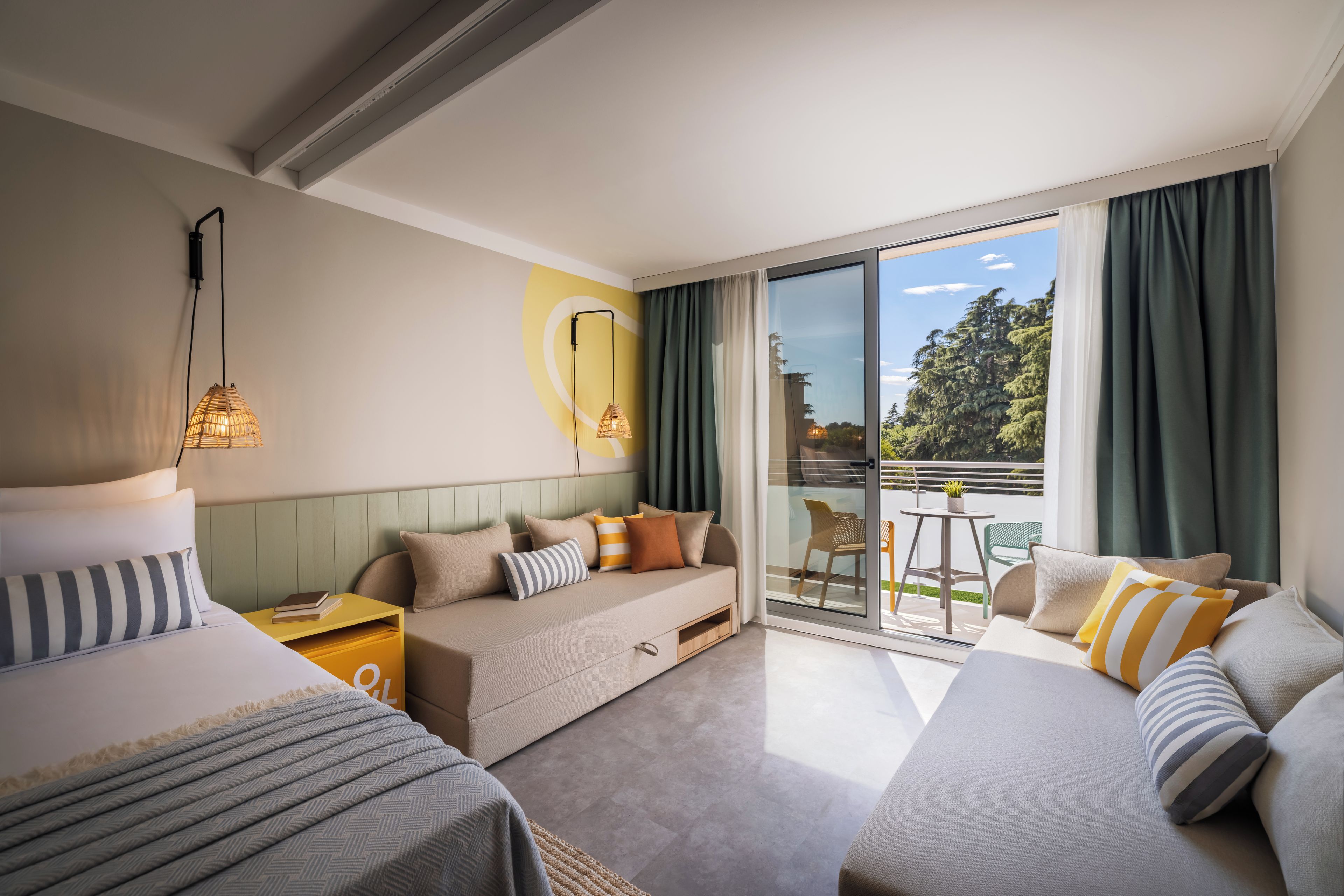 Habitación de hotel con sofá, cama, una mesita y vistas al exterior.