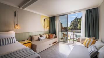 Ein Hotelzimmer mit einer Couch, einem Bett, einem kleinen Tisch und Blick ins Freie.