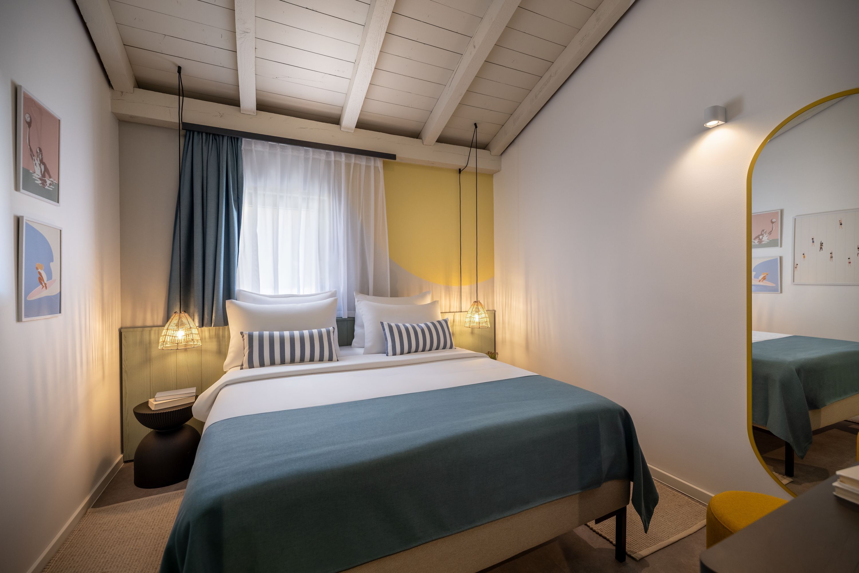 Een slaapkamer met een bed, nachtkastjes, een spiegel en kunst aan de muren.