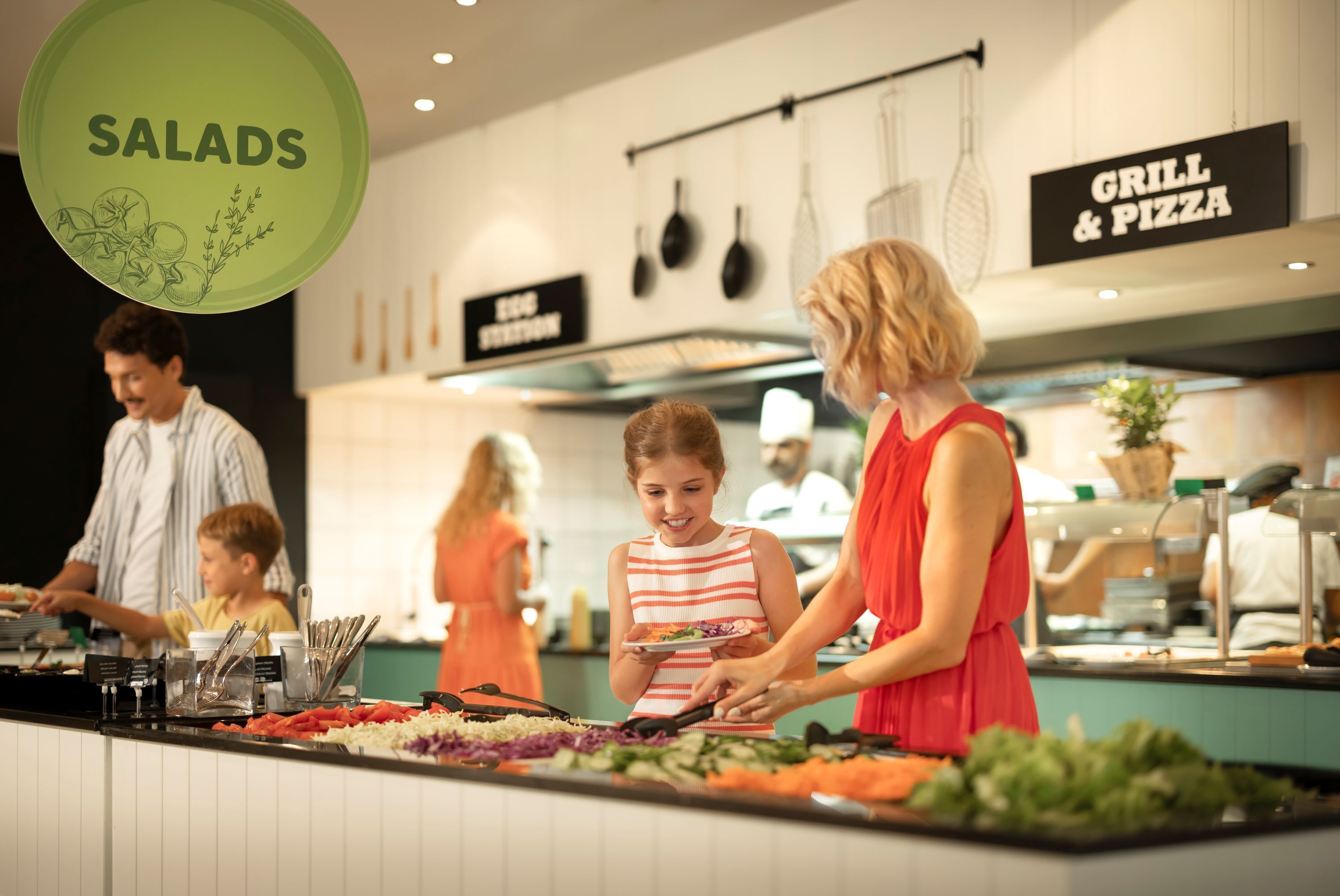 A buffet area with a sign for salads, a grill, and pizza.