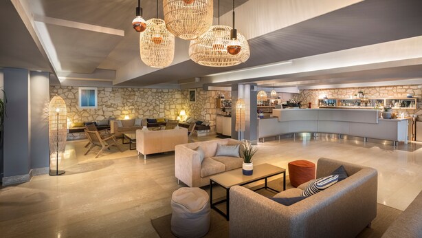 En rymlig entréhall med en vägg av natursten, en bardisk och moderna möbler.