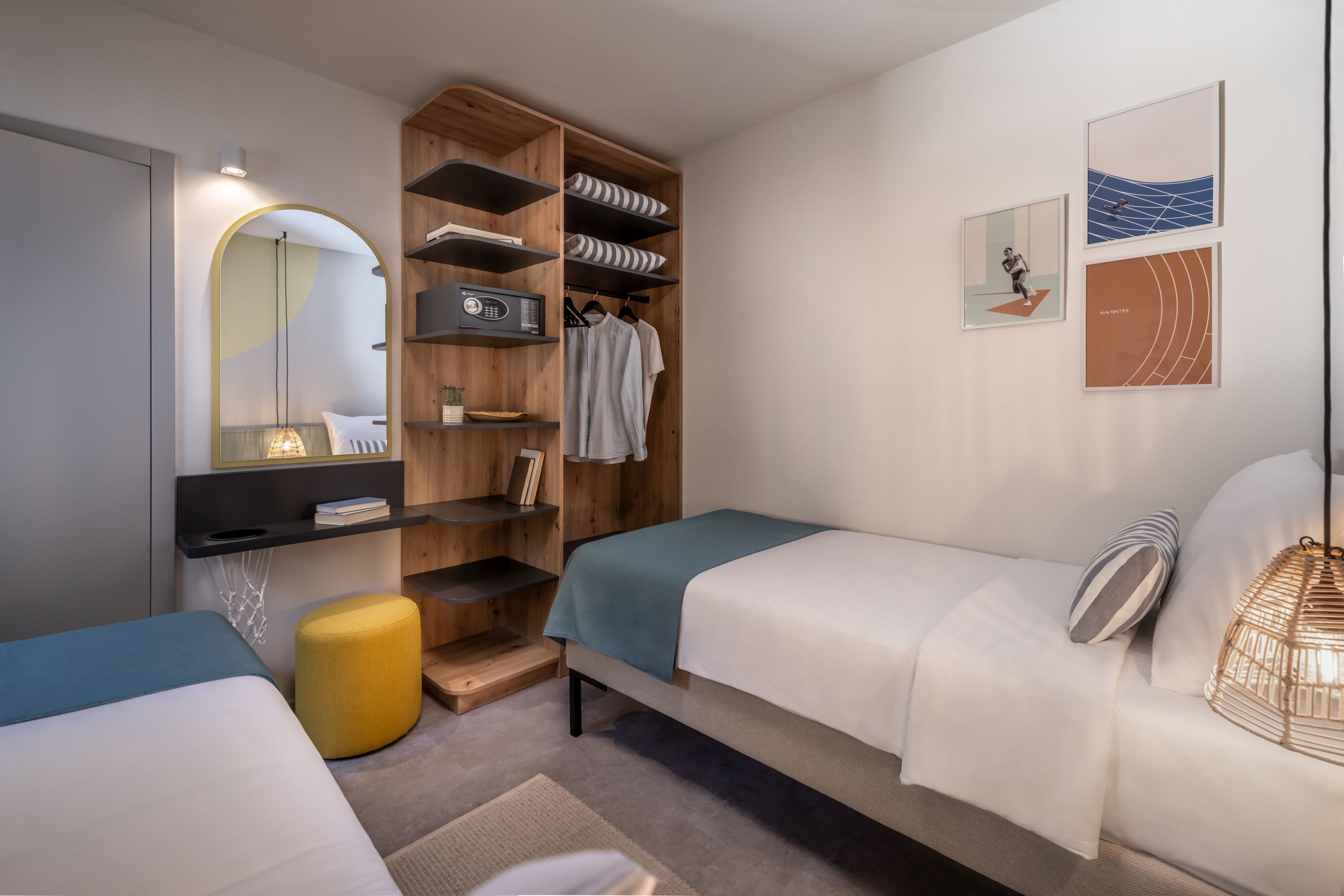 A bedroom with two beds, a wardrobe, a mirror, and artwork on the wall.