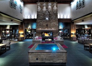 Un amplio hall con chimenea de piedra, asientos cómodos y una zona de piscina.