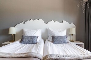 A double bed with white bedding, two bedside lamps, and a decorative headboard. - Santa's Hotel Tunturi (Saariselka)
