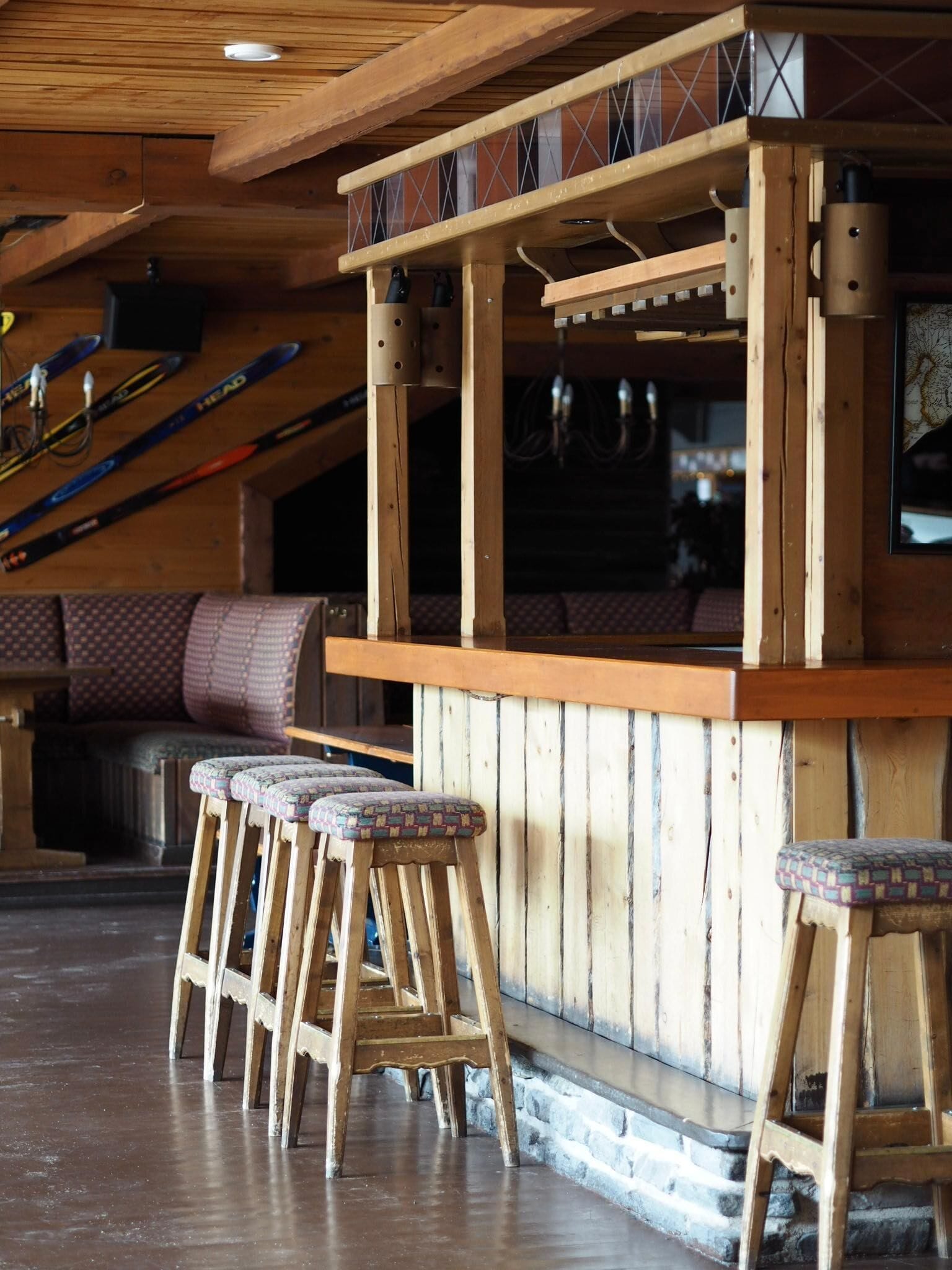 A wooden bar area with stools and skis in the background.