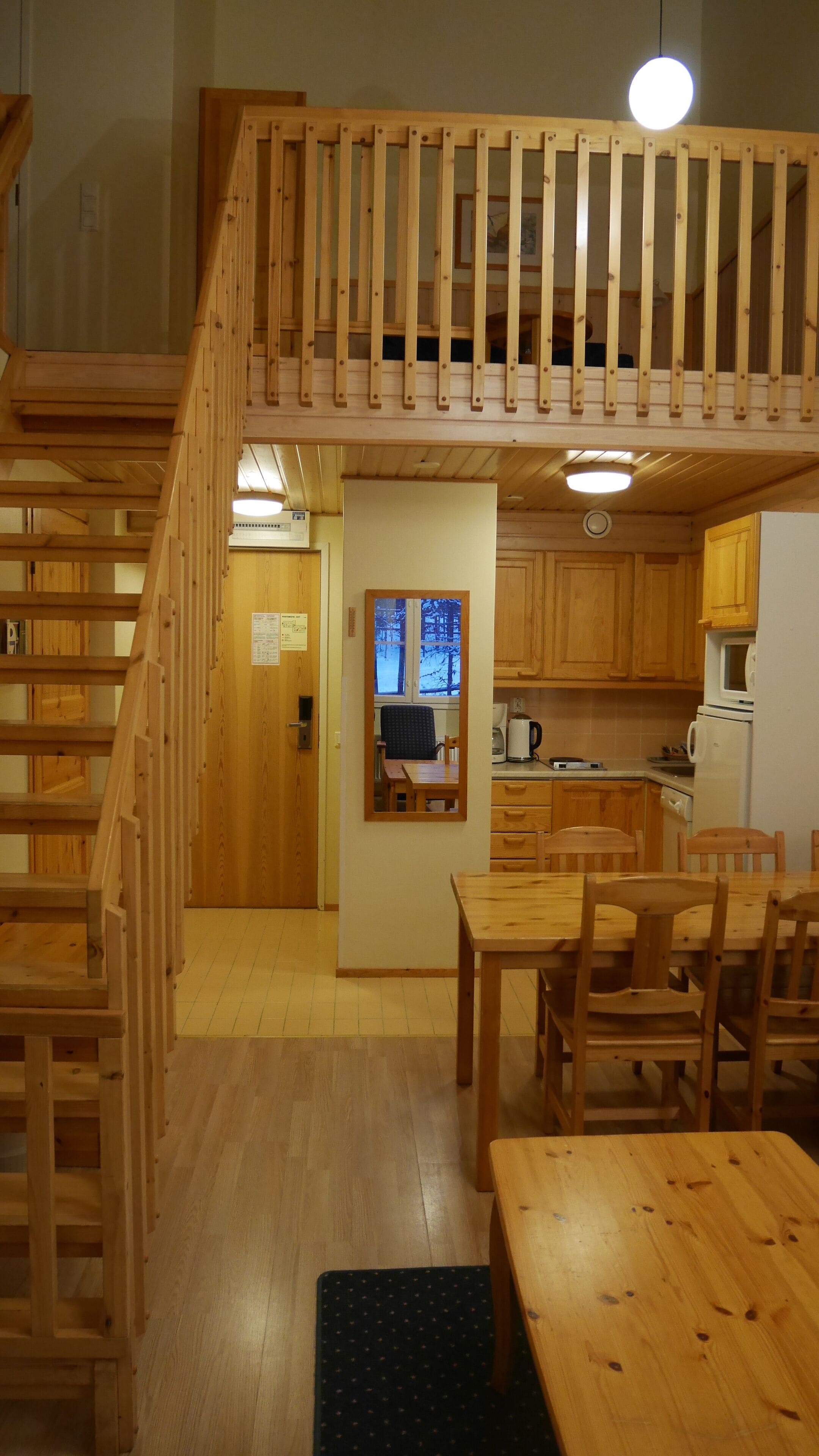 A wooden staircase leading to a lofted area with a kitchen and dining area.