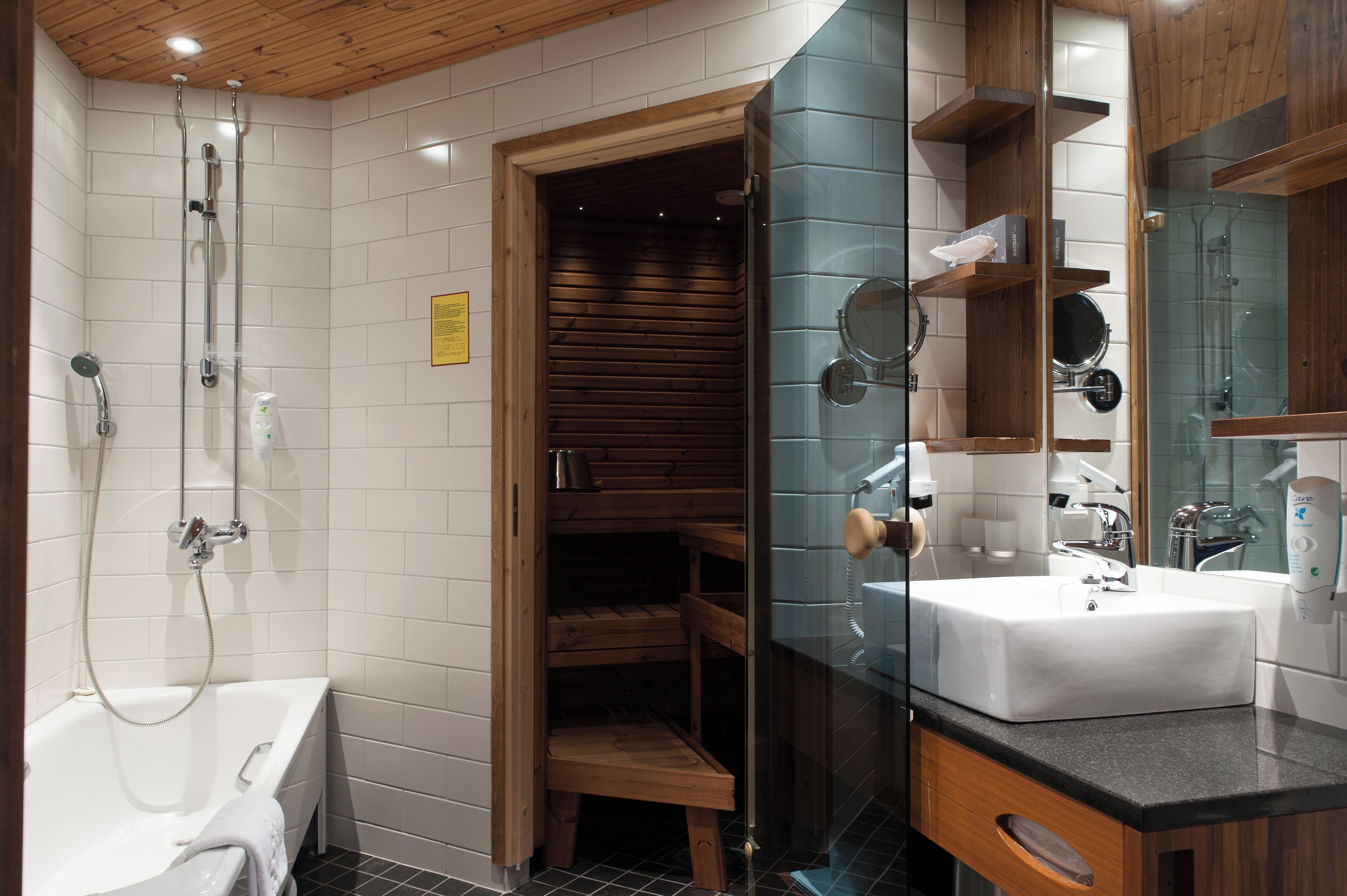 A modern bathroom with a white bathtub, a glass-enclosed shower area, wooden shelves, and a large mirror.