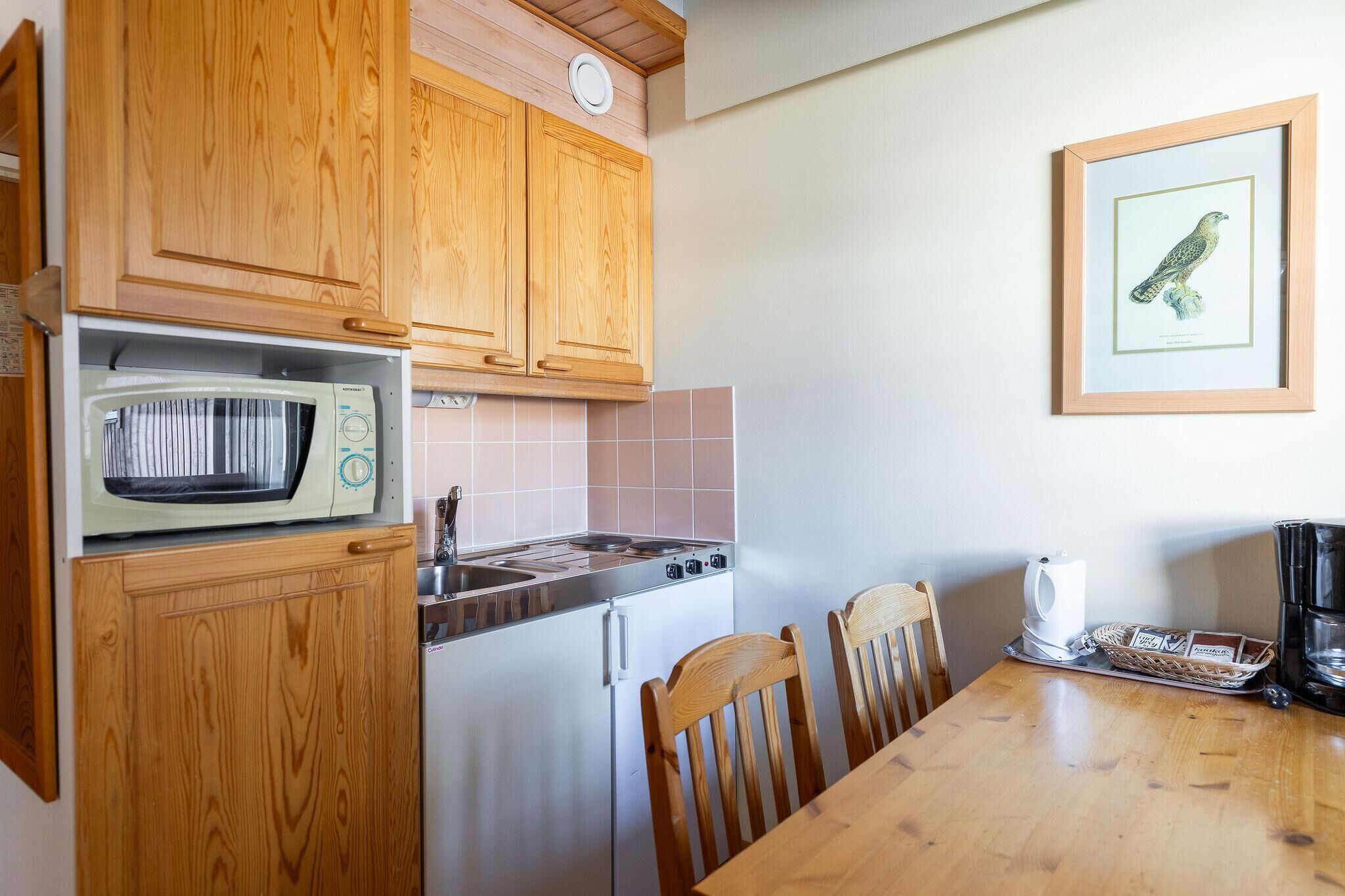 A kitchen with wooden cabinets, a microwave, a stove, a sink, and a dining table with chairs.