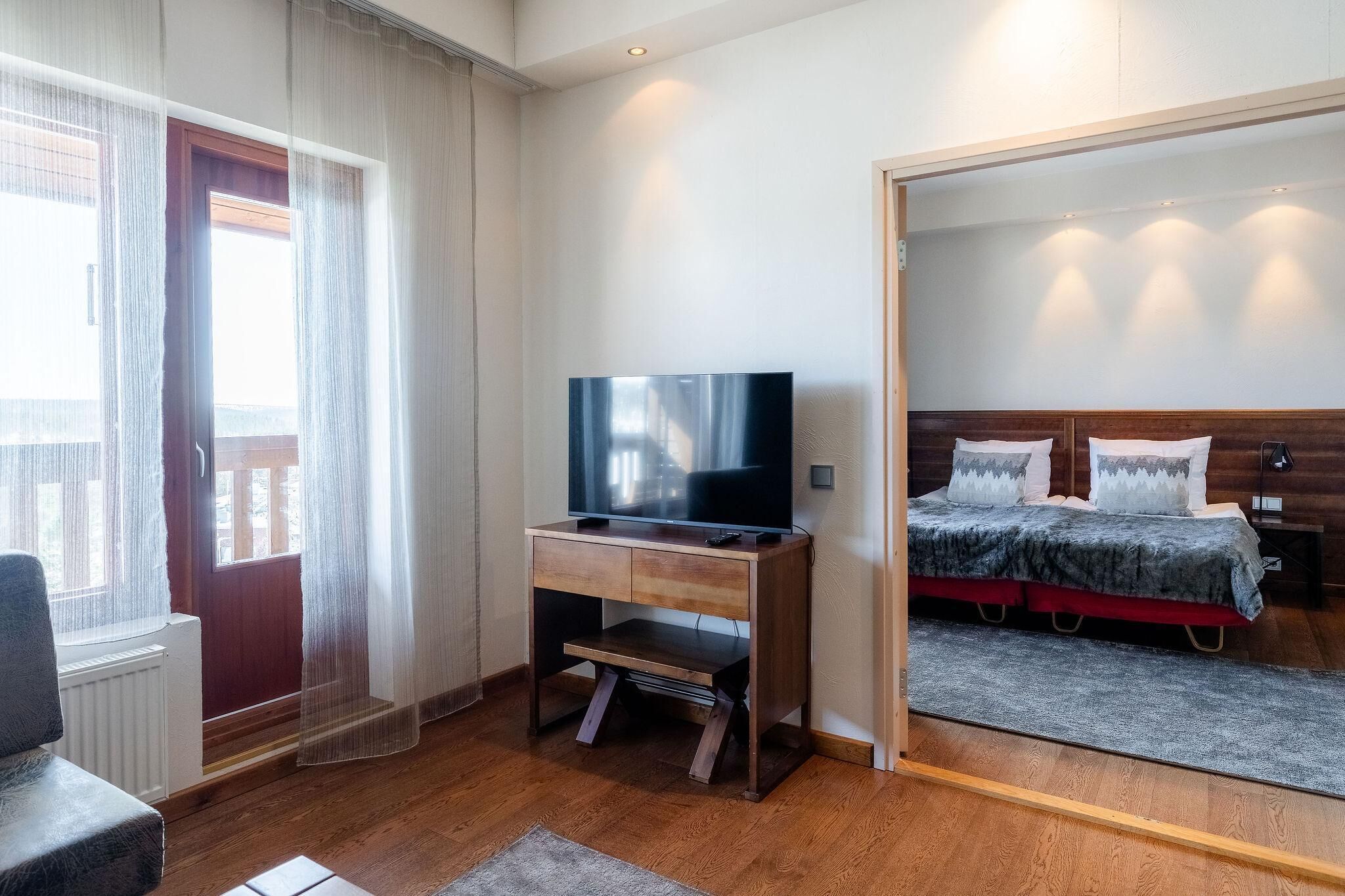 A hotel room with a wooden desk, a television, a bed with pillows, and a large mirror.
