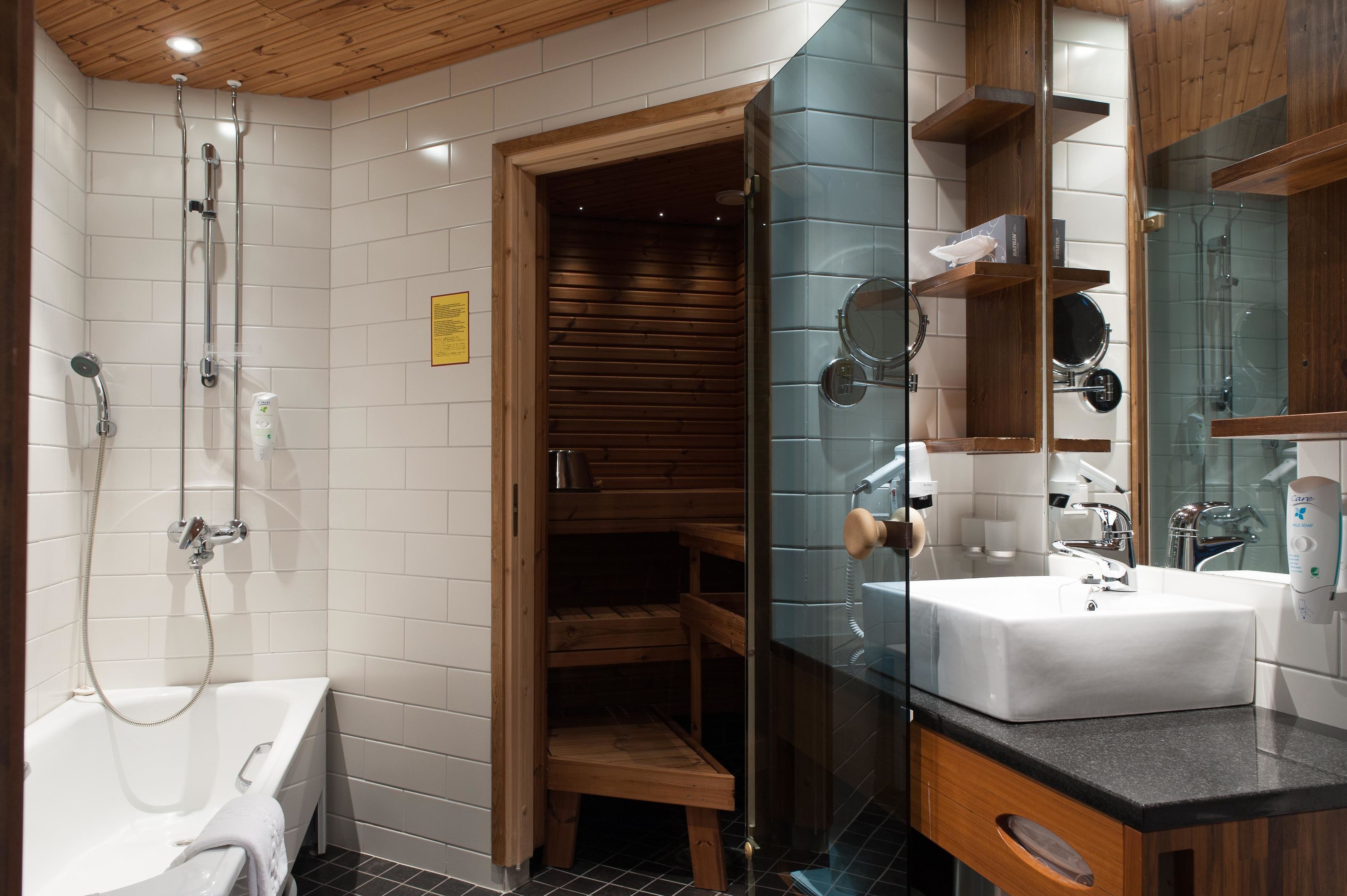 A modern bathroom with a bathtub, glass-enclosed shower, wooden shelves, and a large mirror.