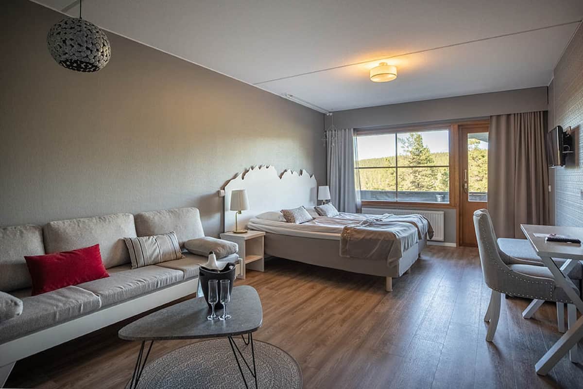 Une chambre d’hôtel moderne équipée d’un canapé, d’un lit, d’une table à manger et d’un téléviseur.