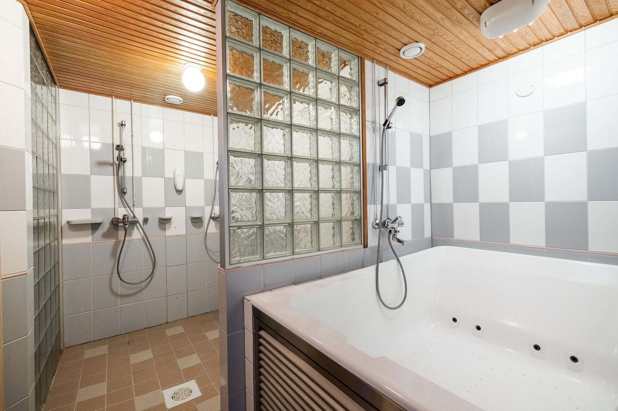 Une salle de bain avec une baignoire, deux douches, une paroi en verre et un plafond en bois.