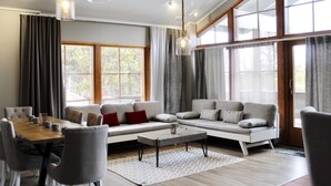 Un salon spacieux avec un grand canapé, une table à manger avec des chaises et de grandes fenêtres dotées de rideaux.