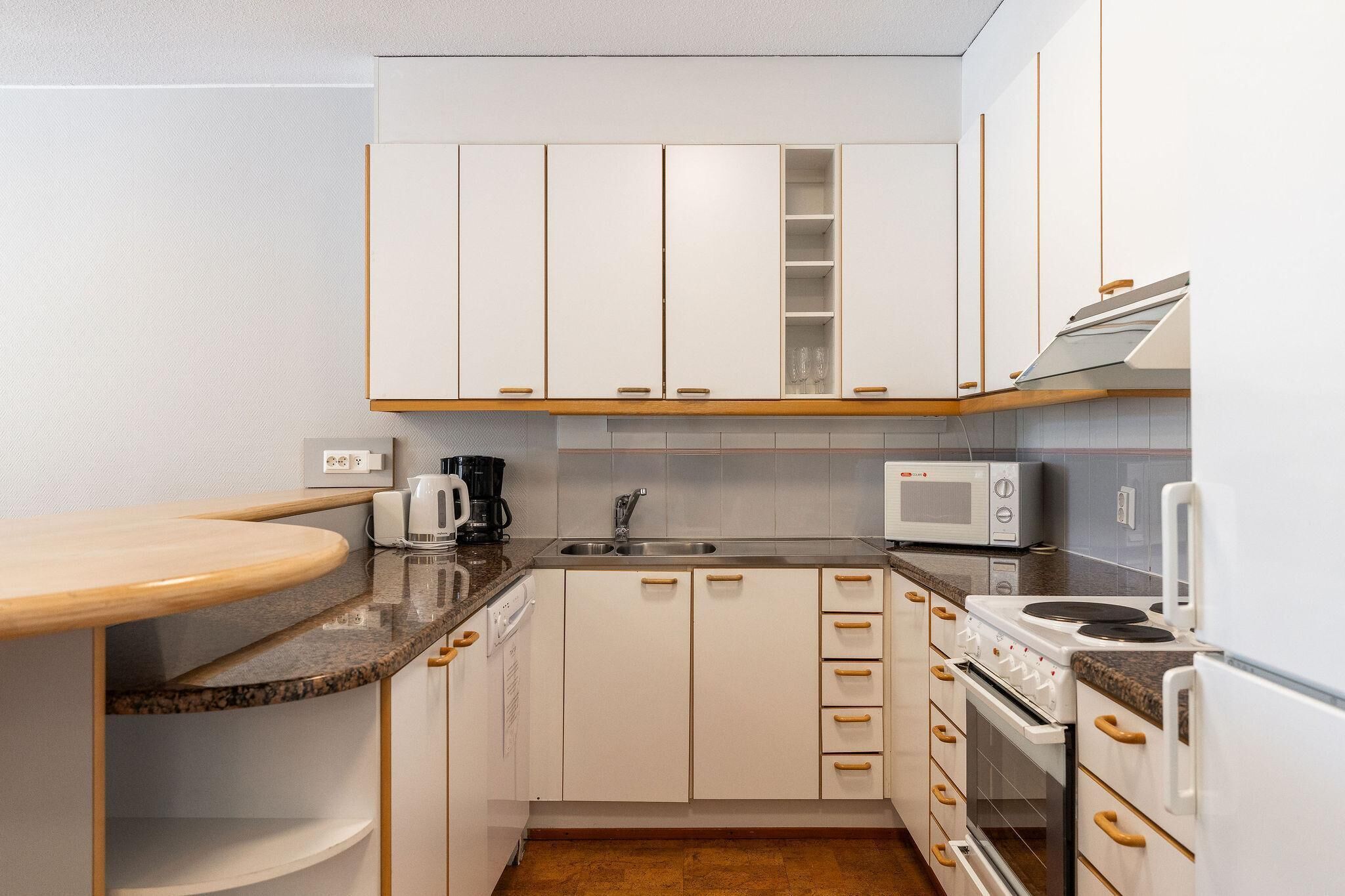 A compact kitchen with white cabinets, a microwave, a stove, and a coffee maker.