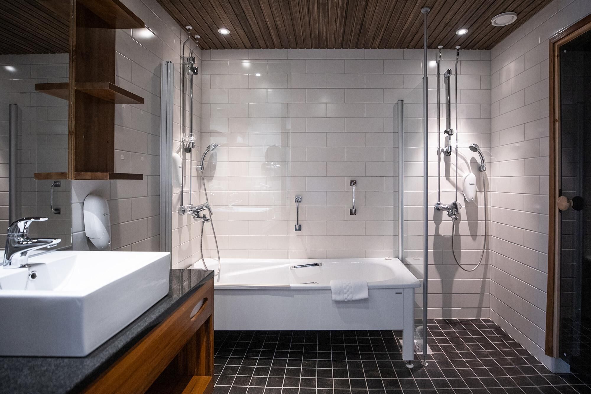 Un baño moderno con bañera, ducha, lavabo y espejo.