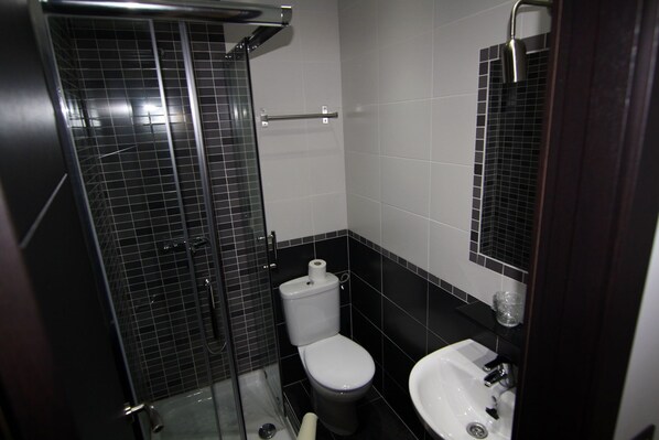 A bathroom with a glass-enclosed shower, a toilet, and a sink. - Hostal MH Fuencarral (Madrid)