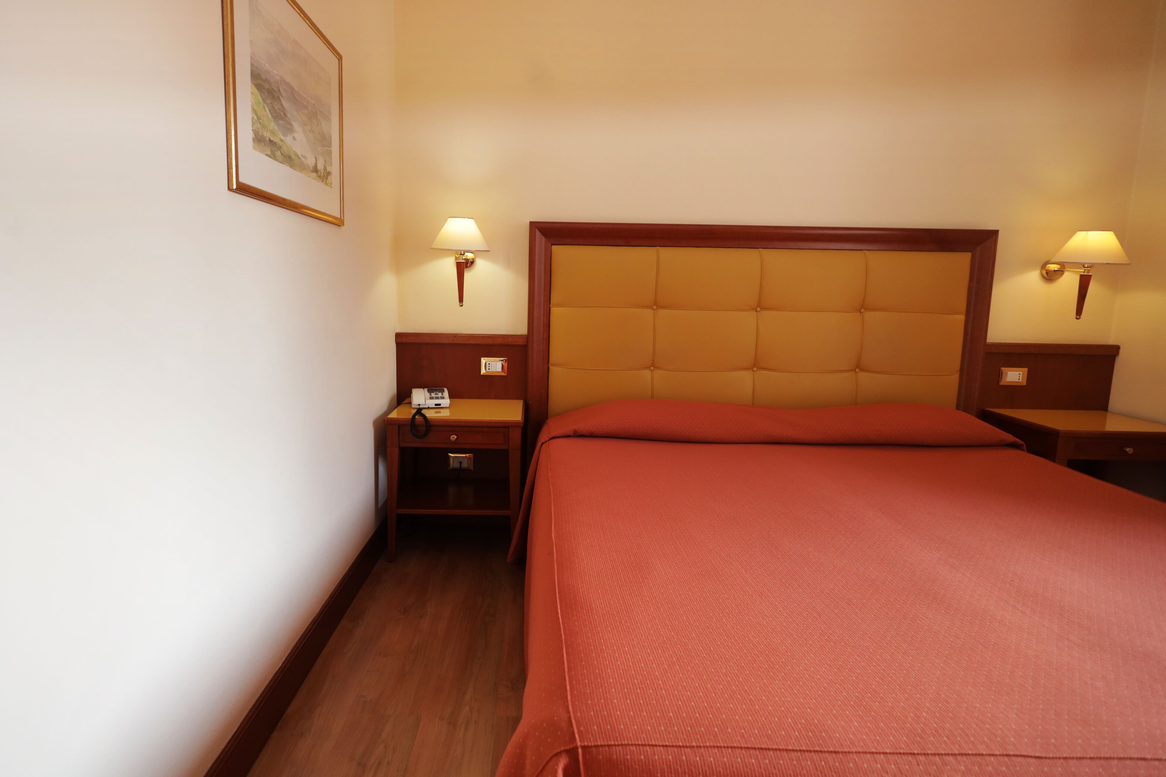 Una habitación de hotel con una cama grande, dos mesitas de noche y dos lámparas de pared.