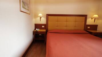 Una habitación de hotel con una cama grande, dos mesitas de noche y dos lámparas de pared.