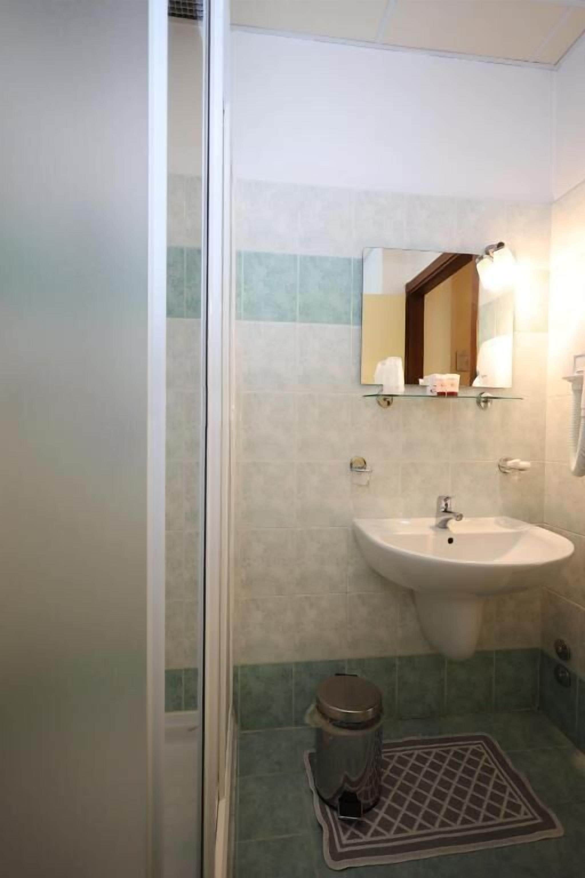 A bathroom with a sink, mirror, and shower.