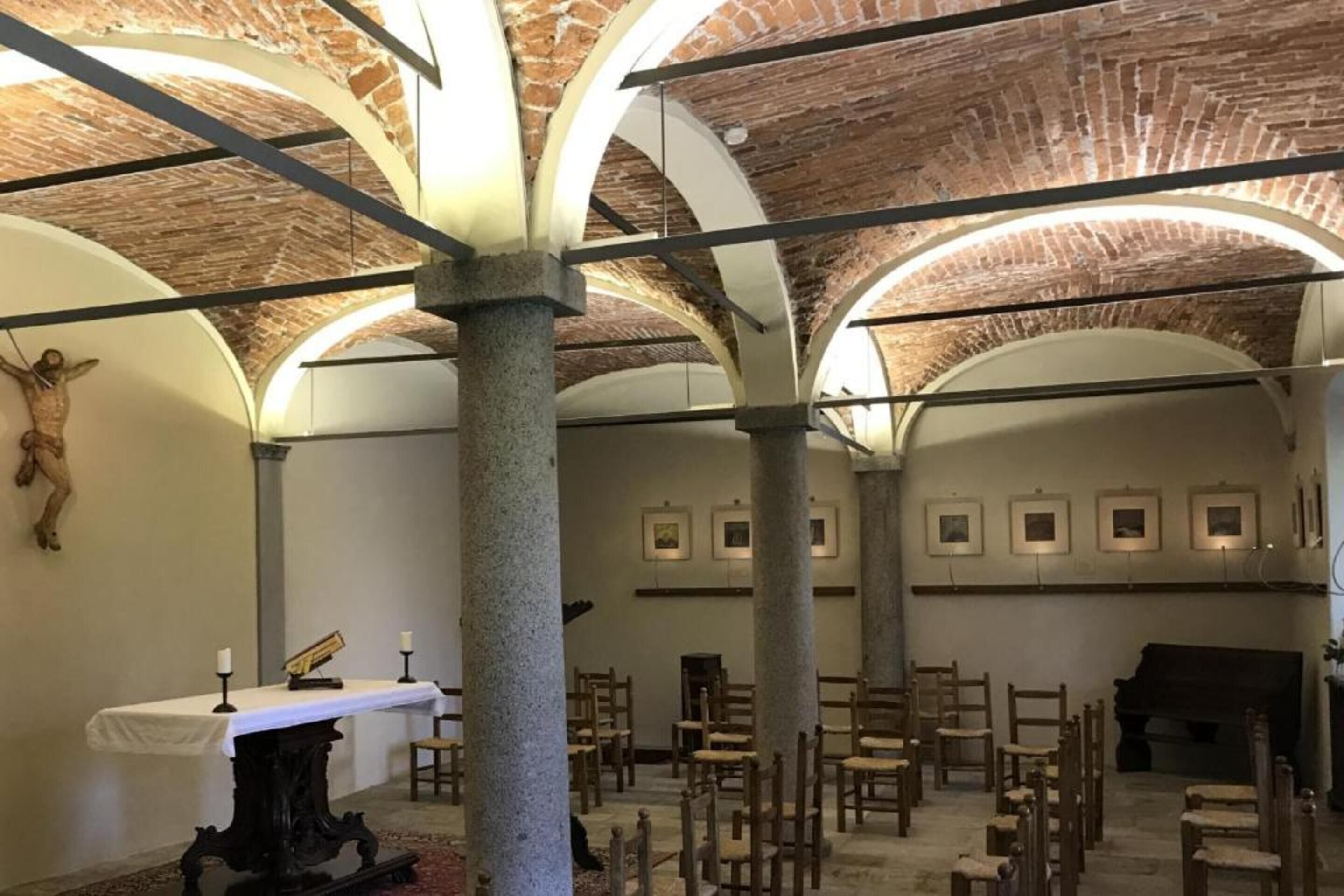 Une chapelle dotée de voûtes en arc, de bancs en bois, d’un piano et d’œuvres d’art religieux sur les murs.