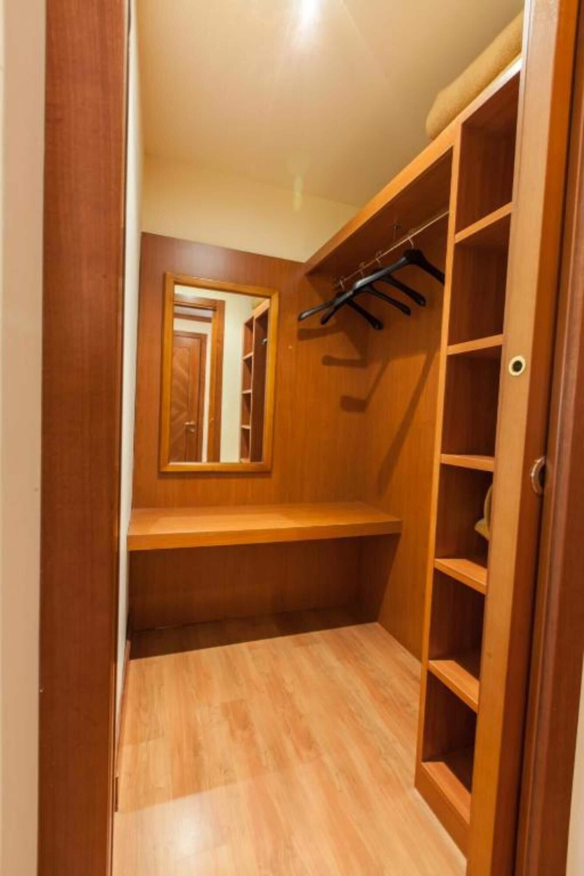 A wooden closet with shelves and a hanging rod.