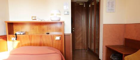 A hotel room with a bed, a desk, a chair, and a small table.