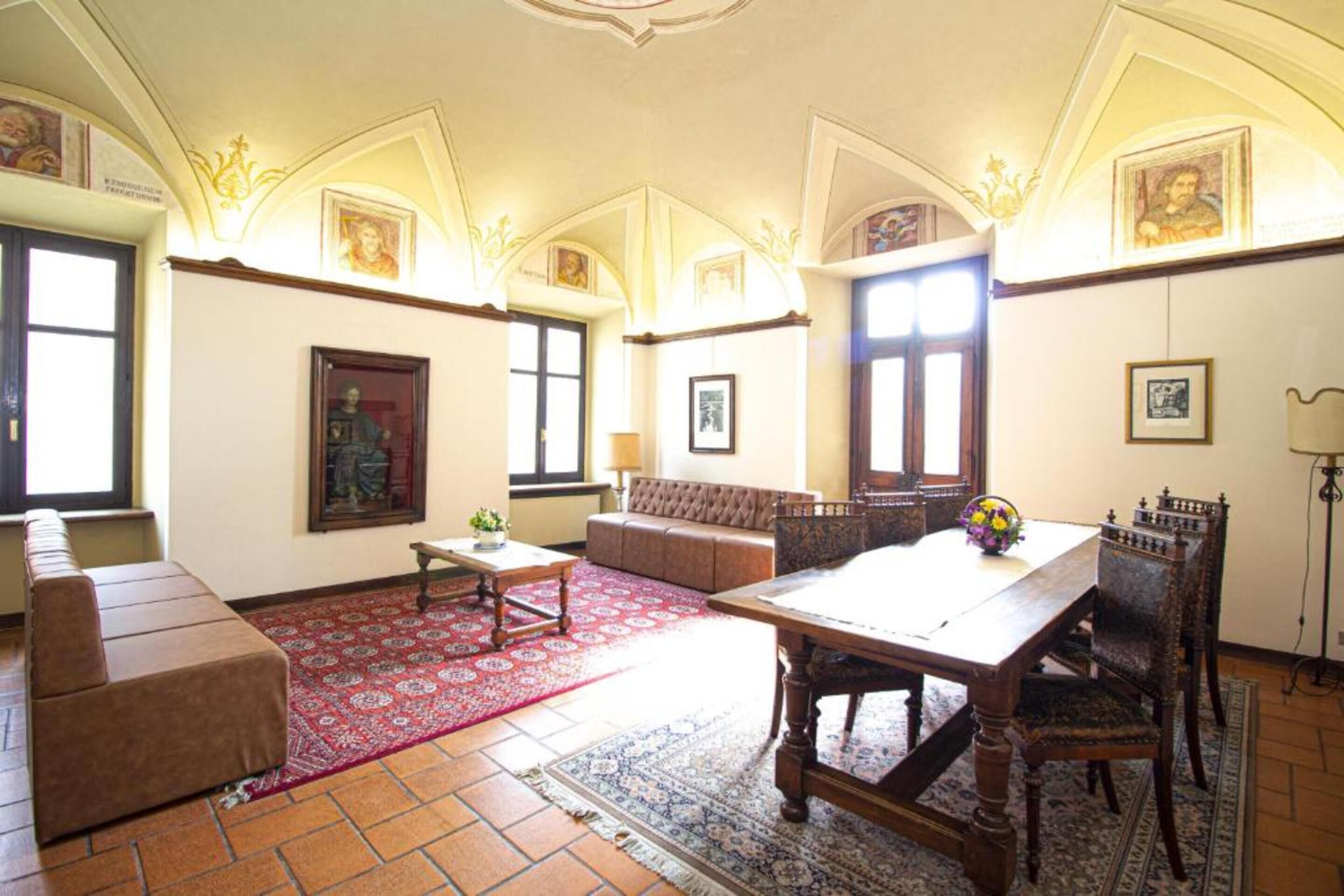 A spacious living room with a large wooden table, a sofa, and a patterned rug.