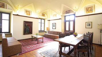 A spacious living room with a large wooden table, a sofa, and a patterned rug.
