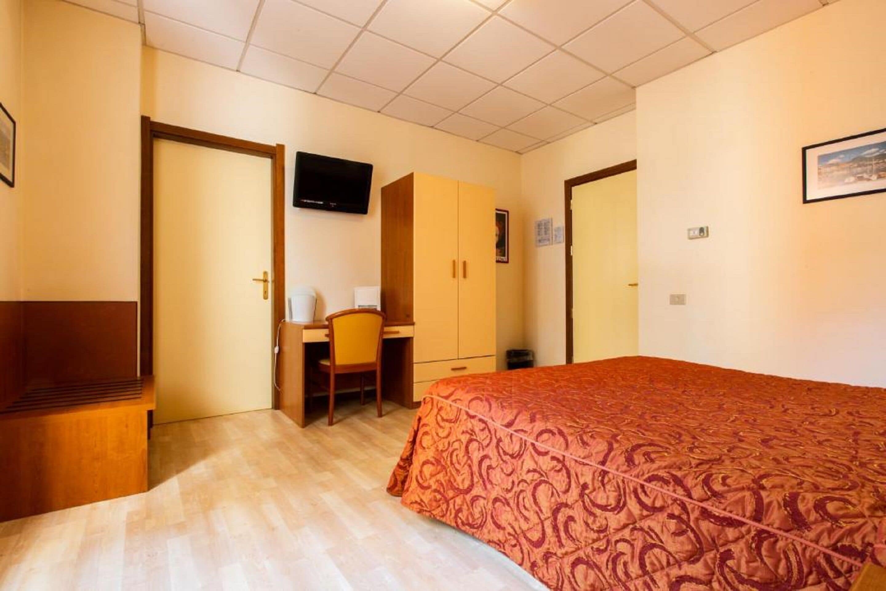 Een hotelkamer met een bed, een bureau, een stoel en een televisie.