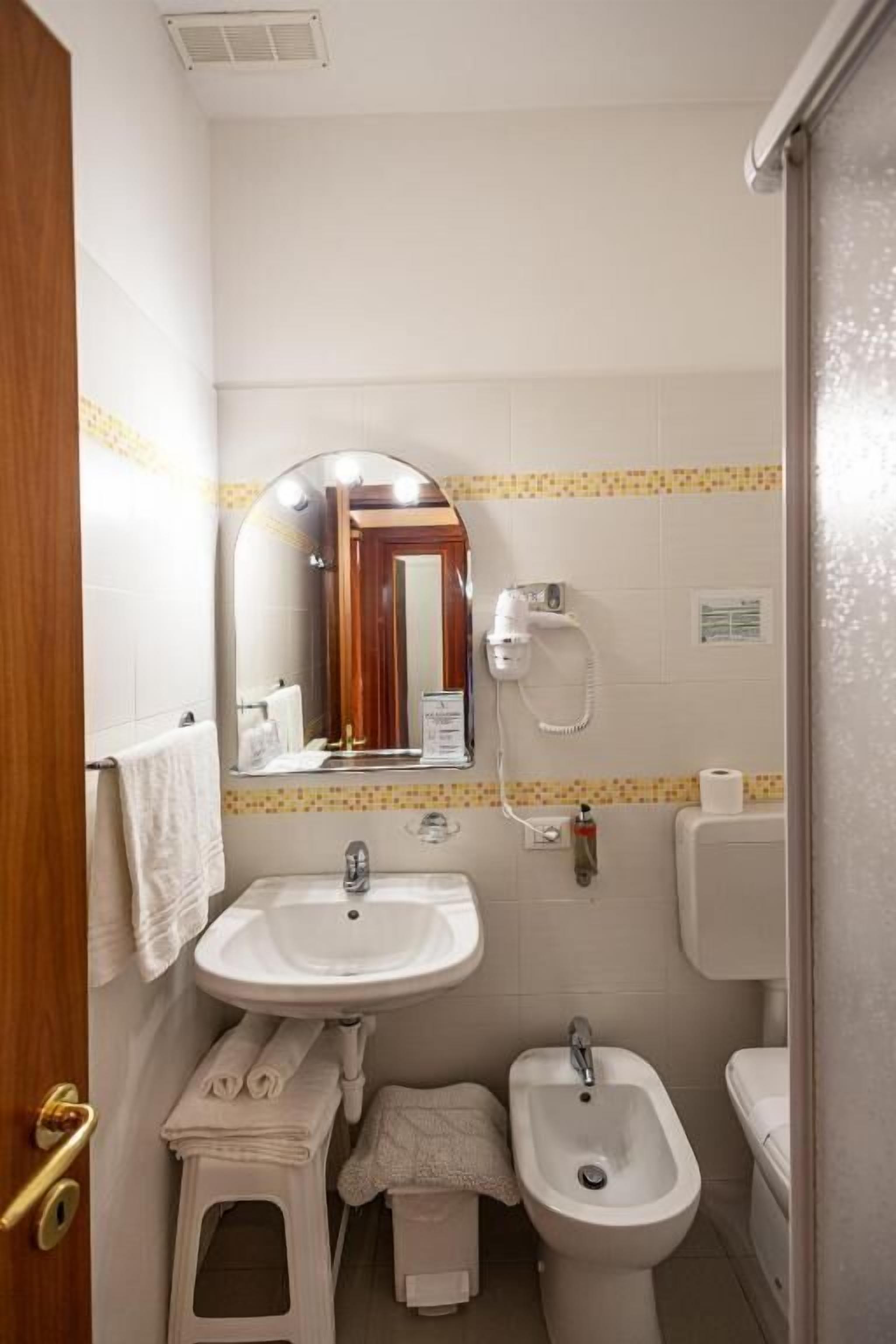A compact bathroom with a sink, bidet, and mirror.