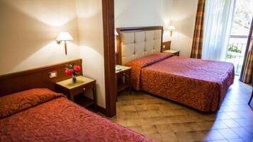 Habitación de hotel con dos camas, una mesita de noche con lámpara y una ventana con cortinas.