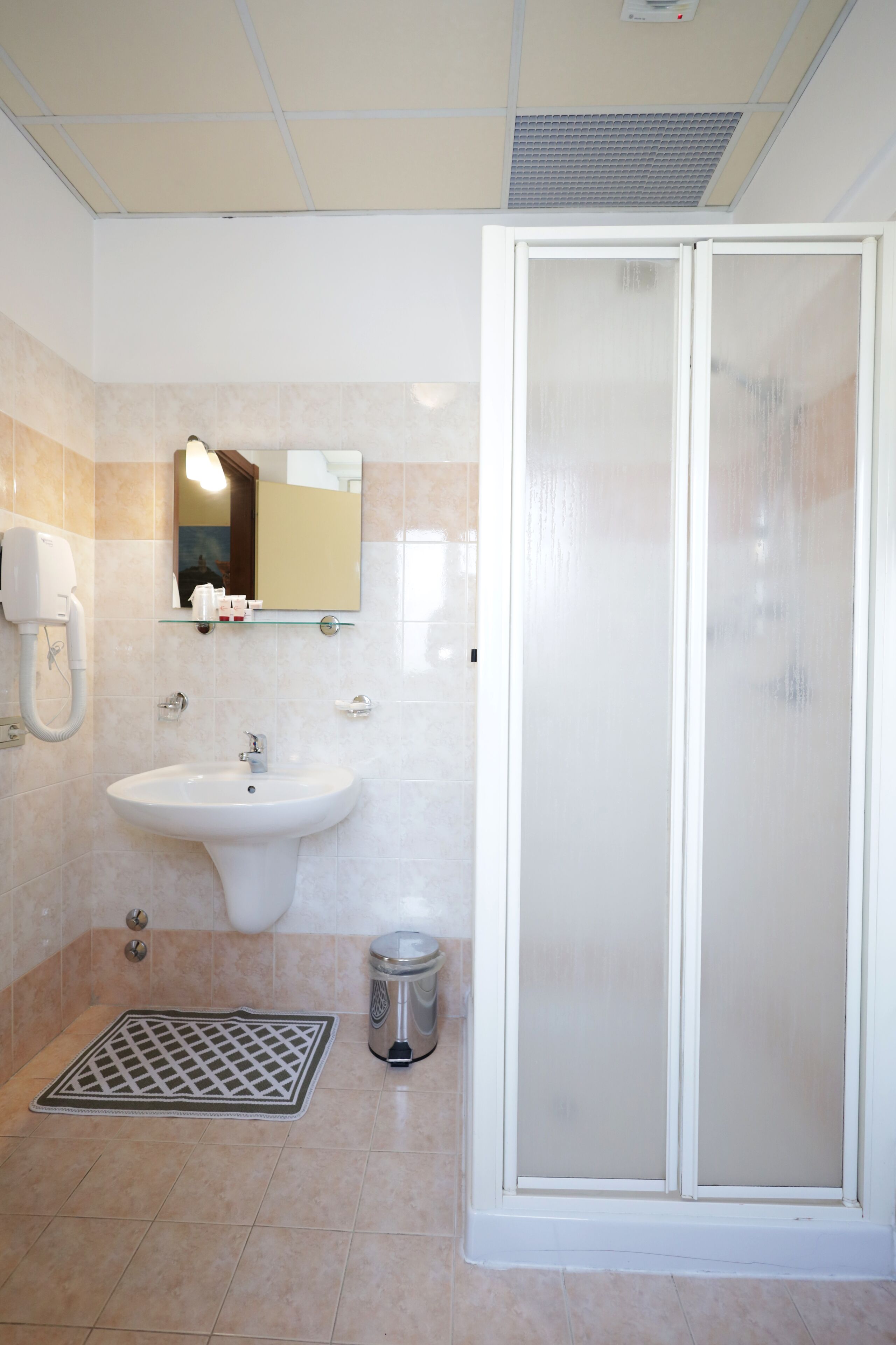 Un baño con lavamanos, espejo y ducha.