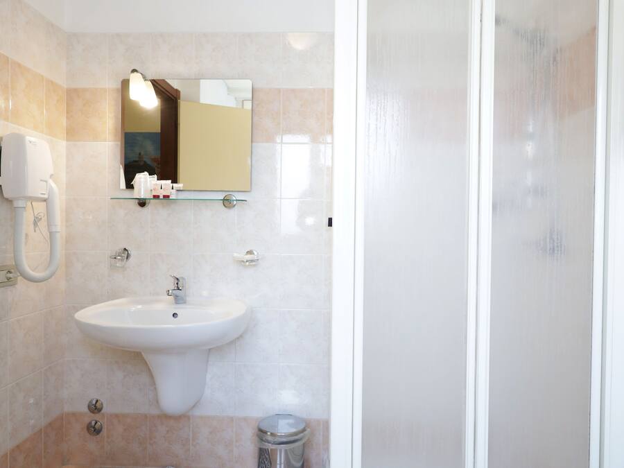 Un baño con lavamanos, espejo y ducha.