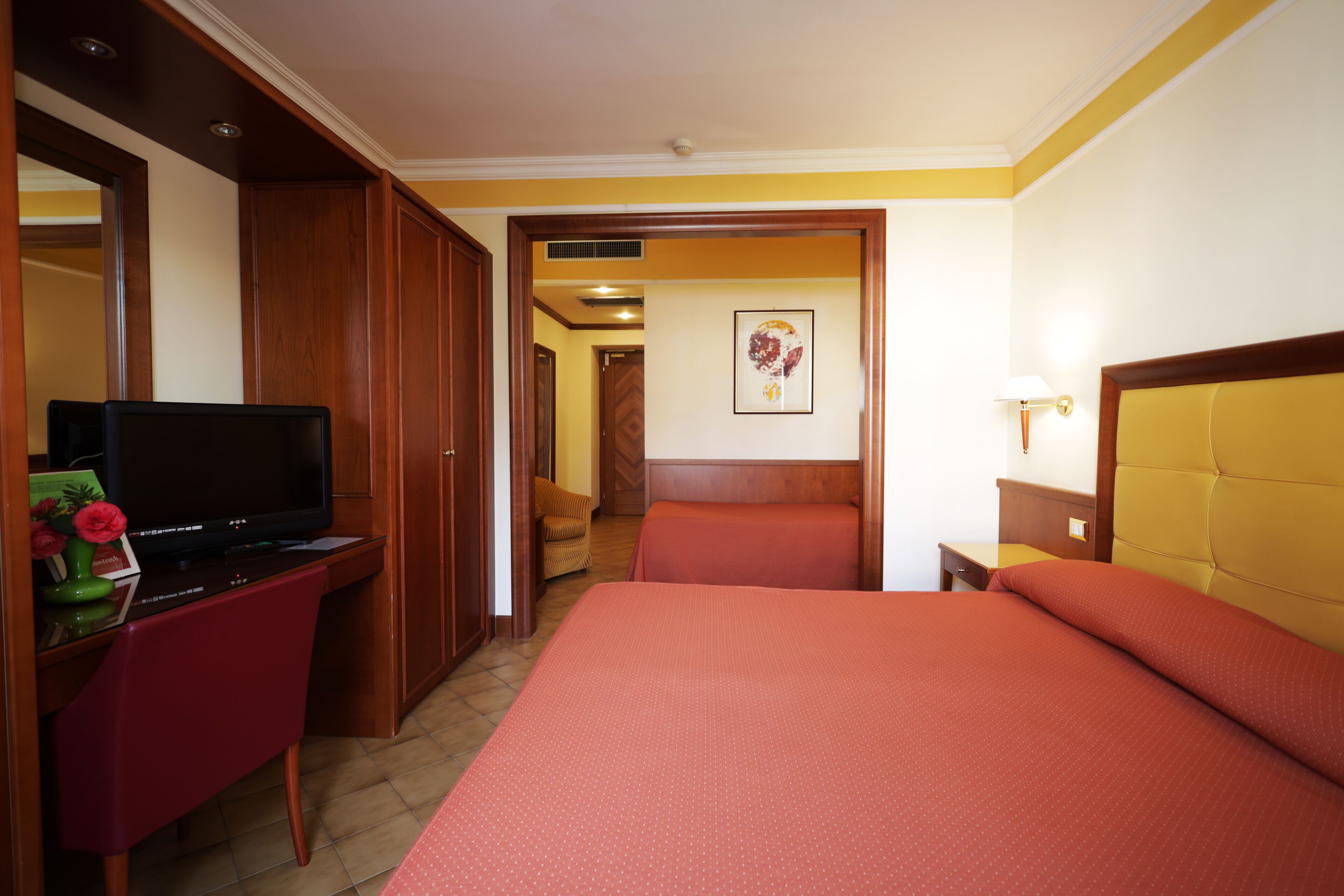 Une chambre d’hôtel avec un lit, une télévision, un bureau et une chaise.