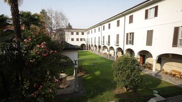 A courtyard with a lawn, a palm tree, and a building with multiple windows and arches.