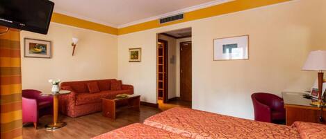 A hotel room with a bed, a sofa, a desk, and a television.