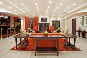 Experience the elegant lobby with a large dining table, comfortable seating, and a stylish fireplace.