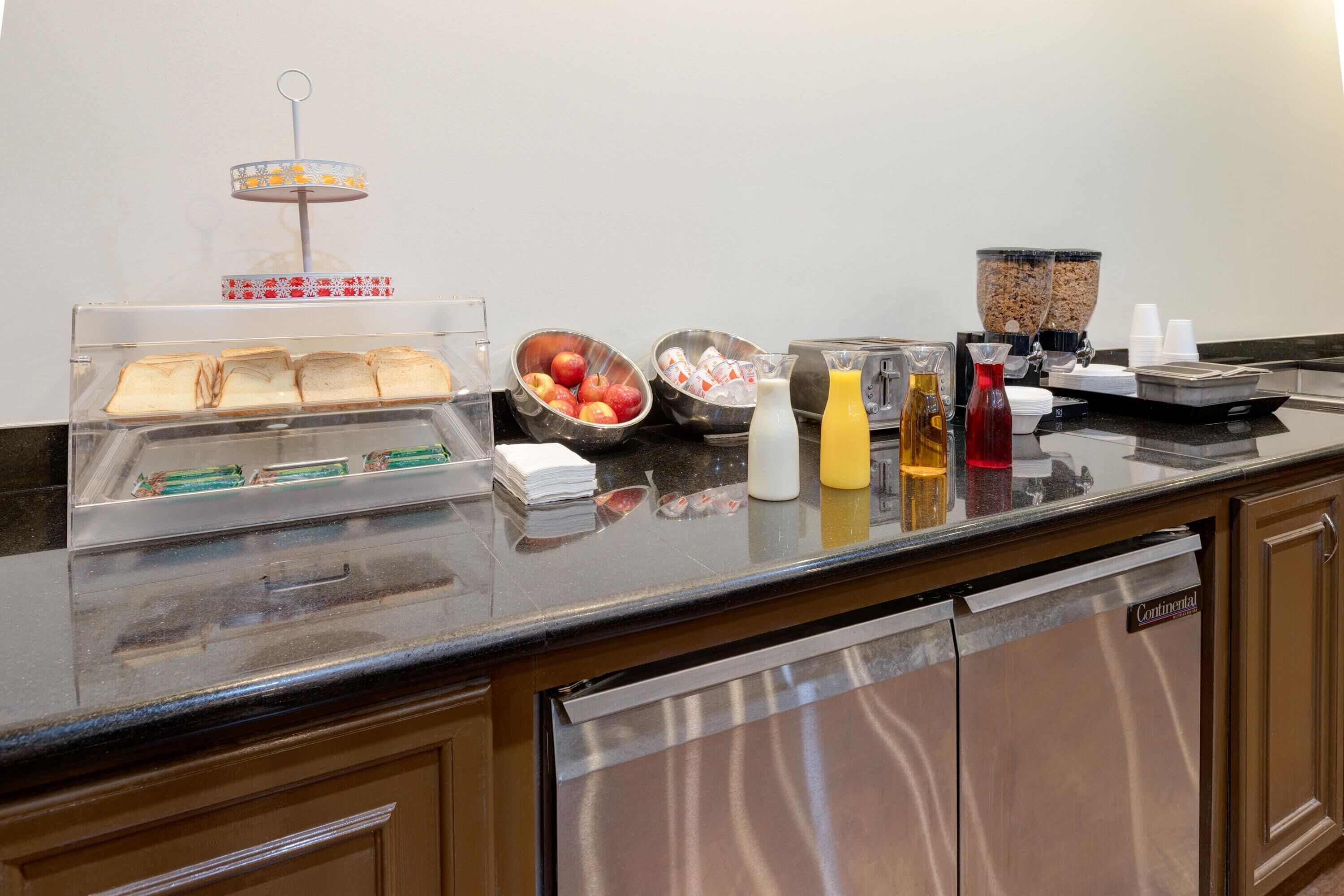 Un bufé de desayuno con panes, frutas y bebidas.