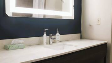 A bathroom with a dark blue accent wall, a white sink, a large mirror, and a towel rack.